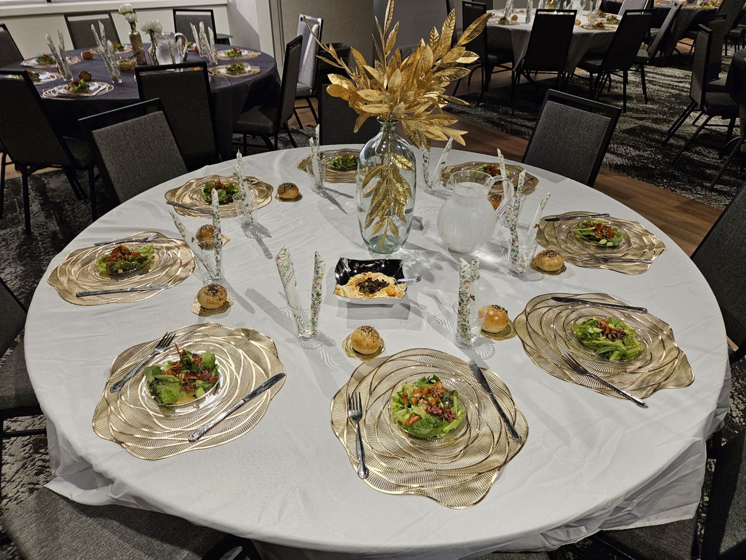 Round banquet table set with gold chargers and salads