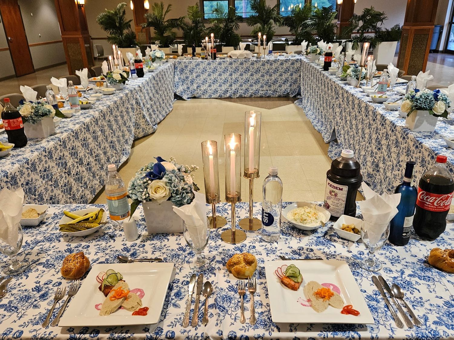 Long banquet tables set with blue and white linens and candles
