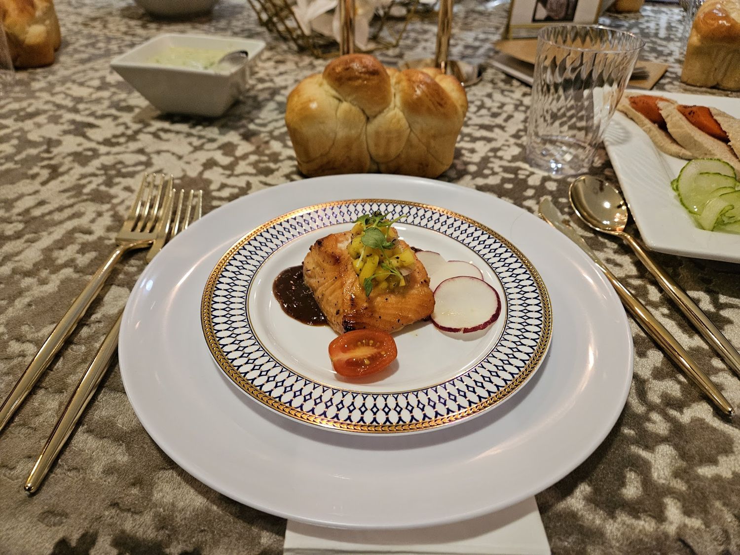 Plated entree and bread rolls on a patterned tablecloth